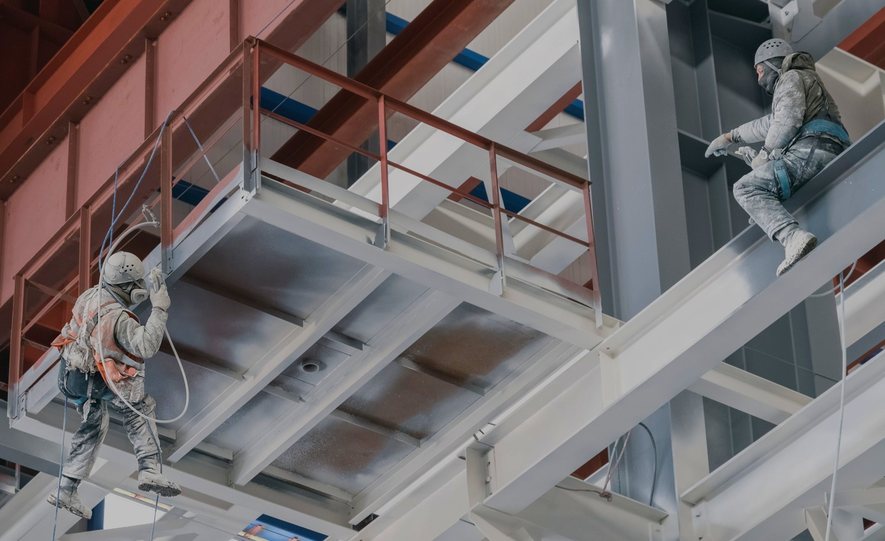 Profissionais aplicando tinta anticorrosiva Eurolatina com pistola airless em estrutura metálica industrial elevada.